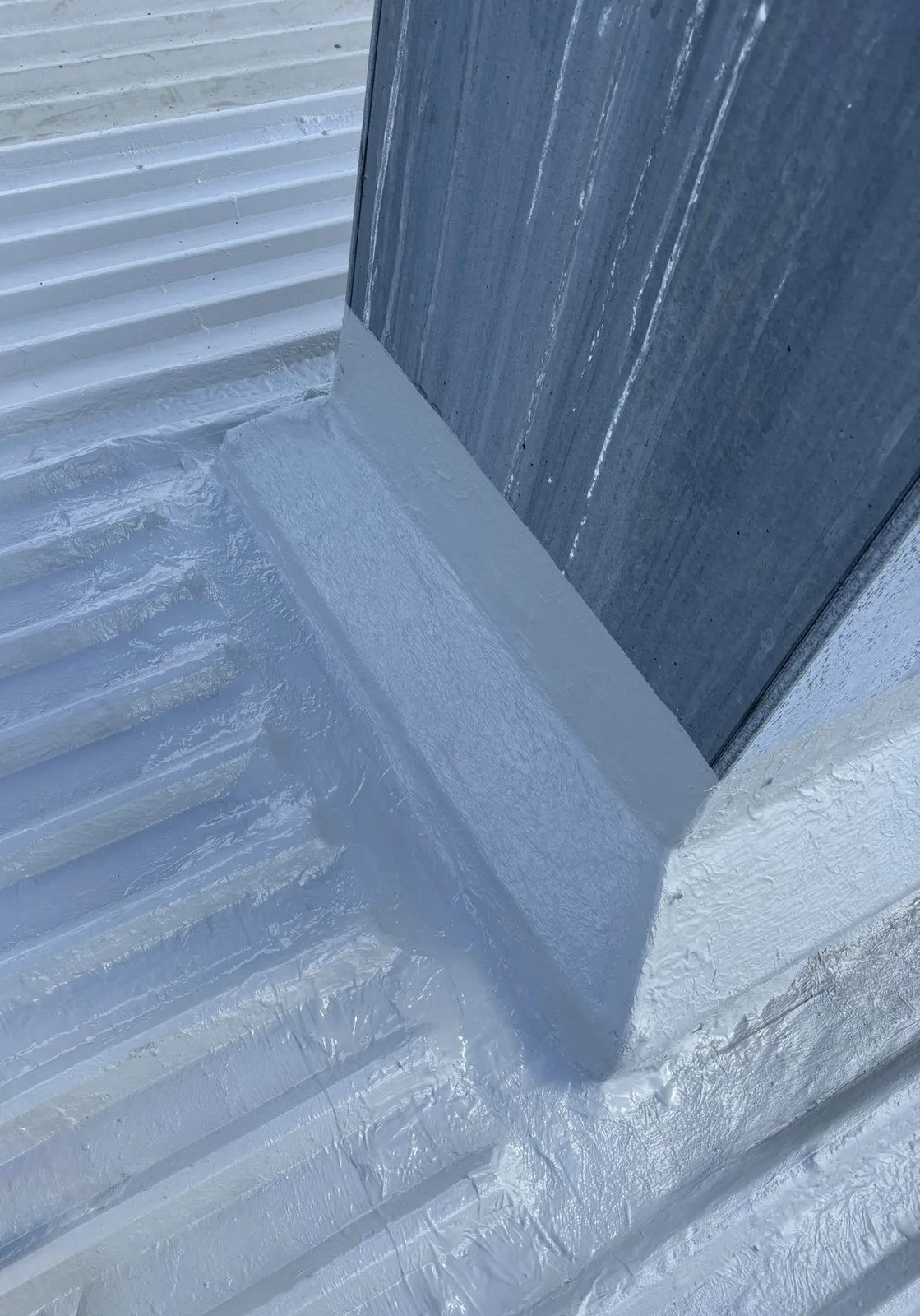 Liquid-applied membrane around a profiled roof upstand detail. System choice and preparation remain roof-specific.
